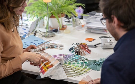 Profesionales de las gafas sentados en una mesa, revisando muestras de color