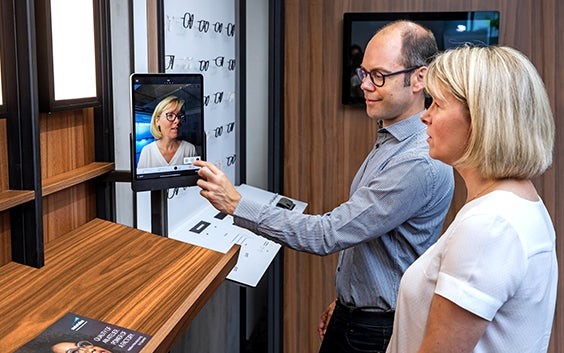 Augenoptiker und Patientin bei der Verwendung des Scanners für die individuelle Anpassung in einem Brillengeschäft