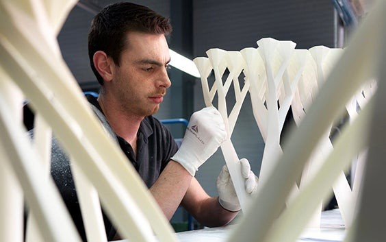 Un homme ponce une table imprimée en 3D pendant la post-production.