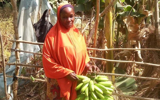 Woman standing outside and holding a bushel of bananas