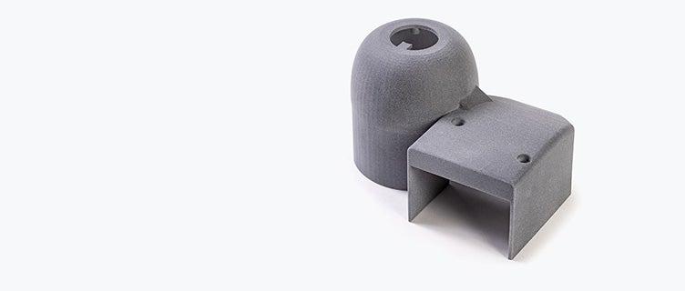 A cylindrical plastic 3D-printed part connected to an open cube-shaped part, printed in PA 12S using Multi Jet Fusion