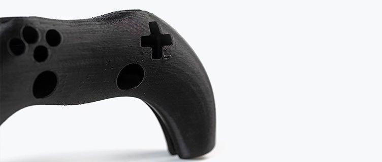A black 3D-printed video game controller printed in ABS-ESD7 using fused deposition modeling.