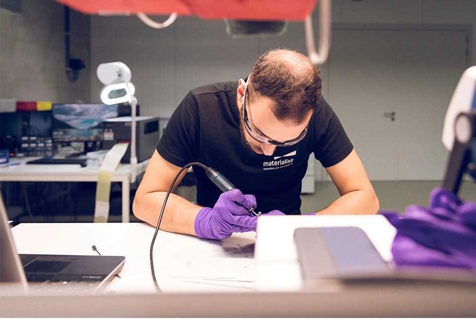 Materialise employee using a tool to finish the surface of a 3D-printed part