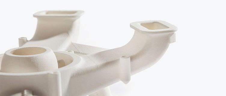 Close-up view of an off-white air duct with multiple curved openings, 3D printed in a halogen-free flame-retardant polyamide.