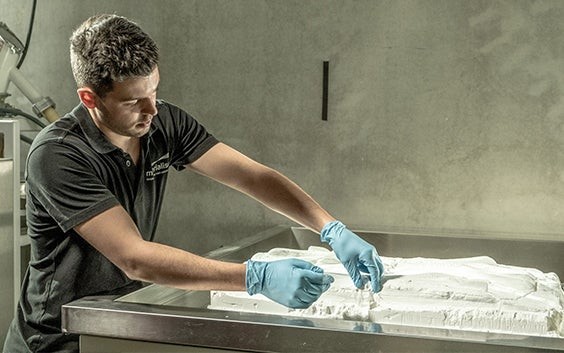 Man taking 3D-printed parts out of a powder bed