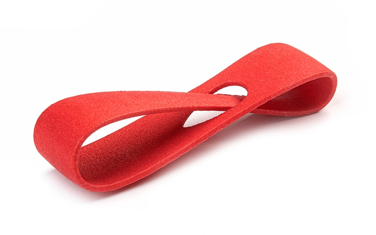 Un bucle rojo impreso en 3D fabricado con PA 12 mediante sinterización láser, con un acabado suave y teñido de color.