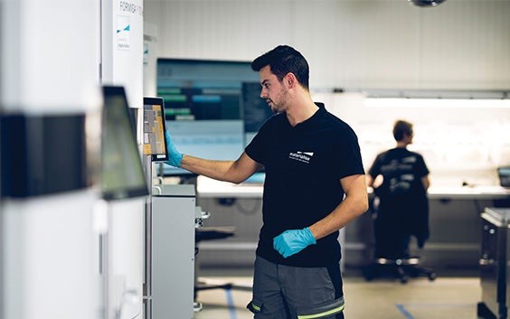 Ein Mitarbeiter von Materialise betrachtet im Produktionsbereich einen Bildschirm eines 3D-Druckers